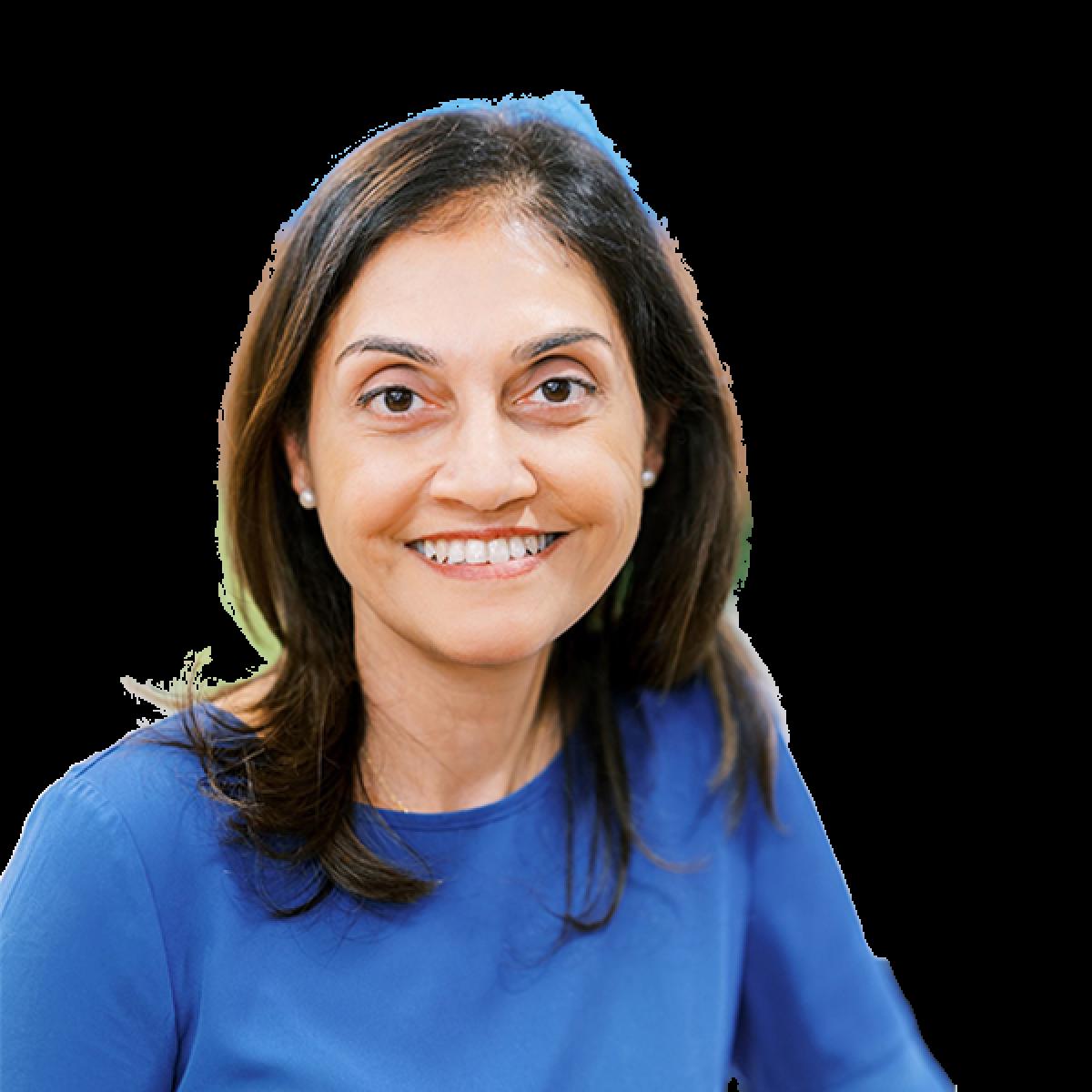 Professional headshot of female healthcare practitioner smiling at camera wearing blue medical uniform