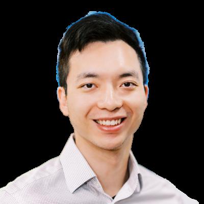 Professional headshot of smiling Asian male doctor in light grey checkered shirt against white background