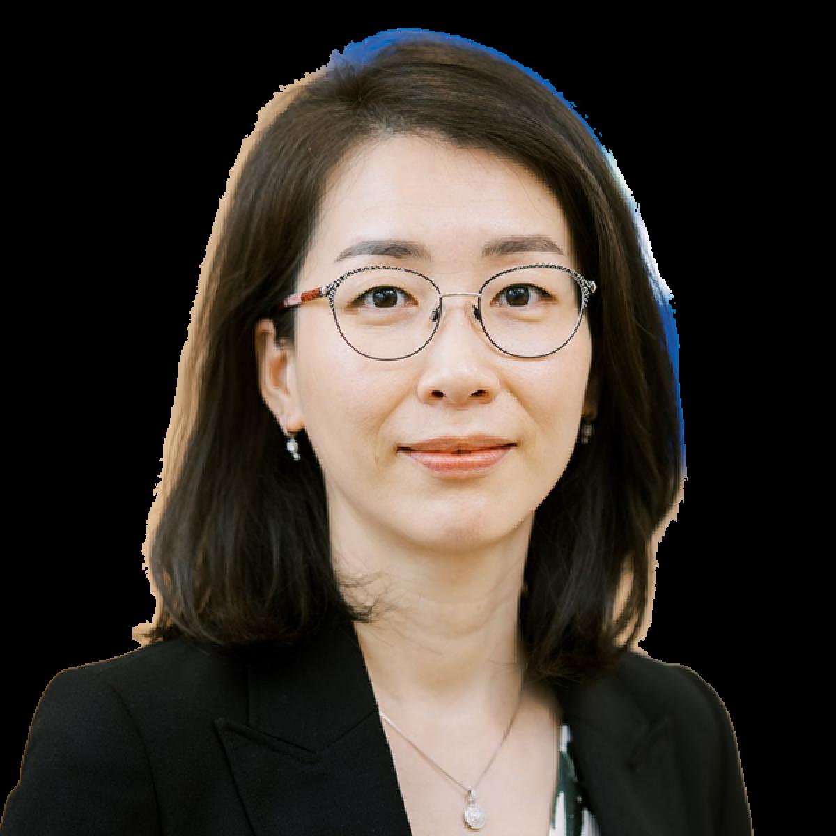 Professional headshot of Asian female doctor wearing glasses and black blazer against white background