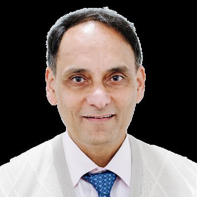 Professional headshot of male doctor in white coat with blue patterned tie smiling at camera