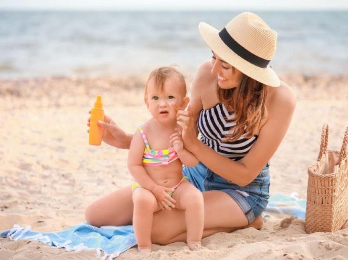 Mother applying sunscreen to toddler on beach during summer holiday