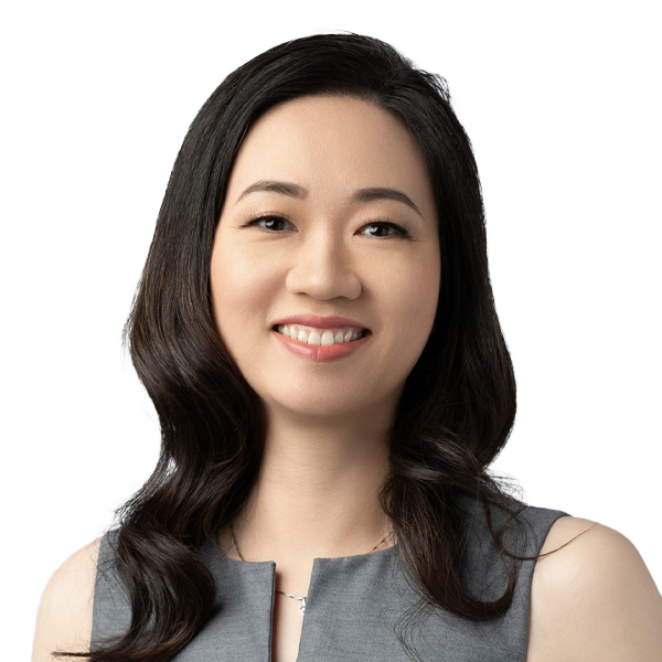 Professional female doctor smiling warmly at camera in grey medical attire against white background