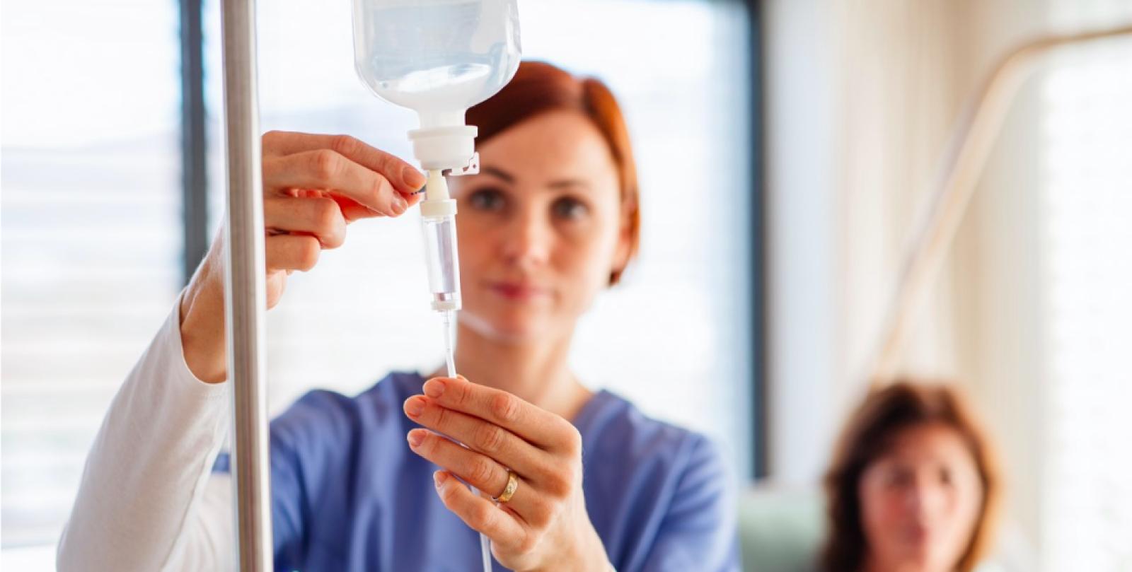 Healthcare professional adjusting IV drip infusion in modern medical clinic setting