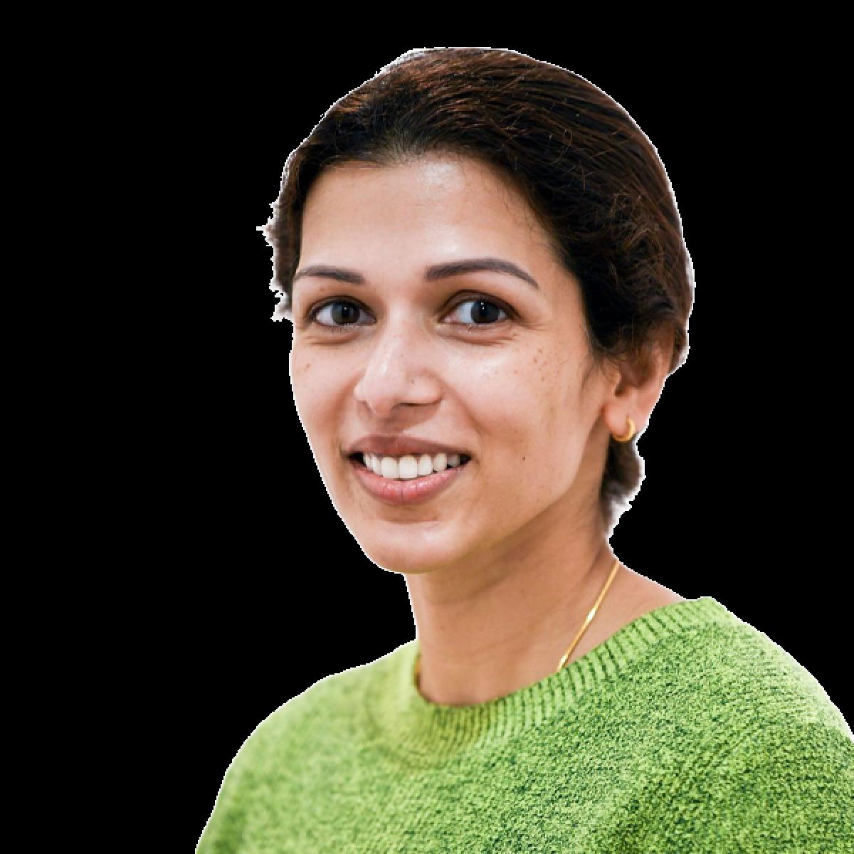 Smiling female healthcare professional wearing a green jumper against a white background