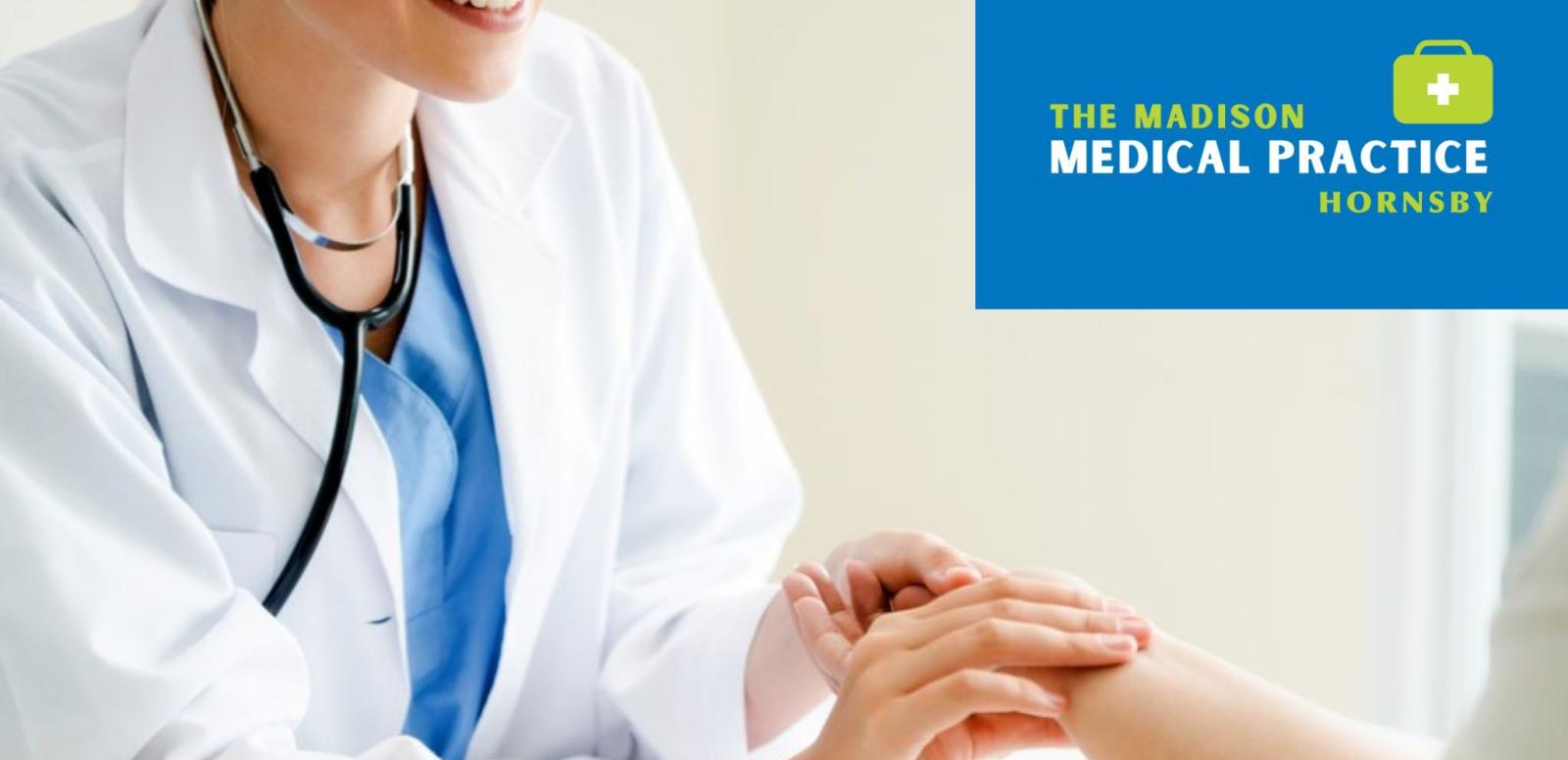 Female doctor in white coat with stethoscope examining patient's hand during medical consultation